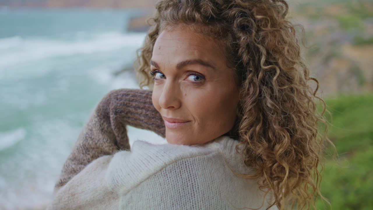Primo piano di una donna attraente che posa in riva al mare in una giornata ventosa e cupa. Ritratto di donna.