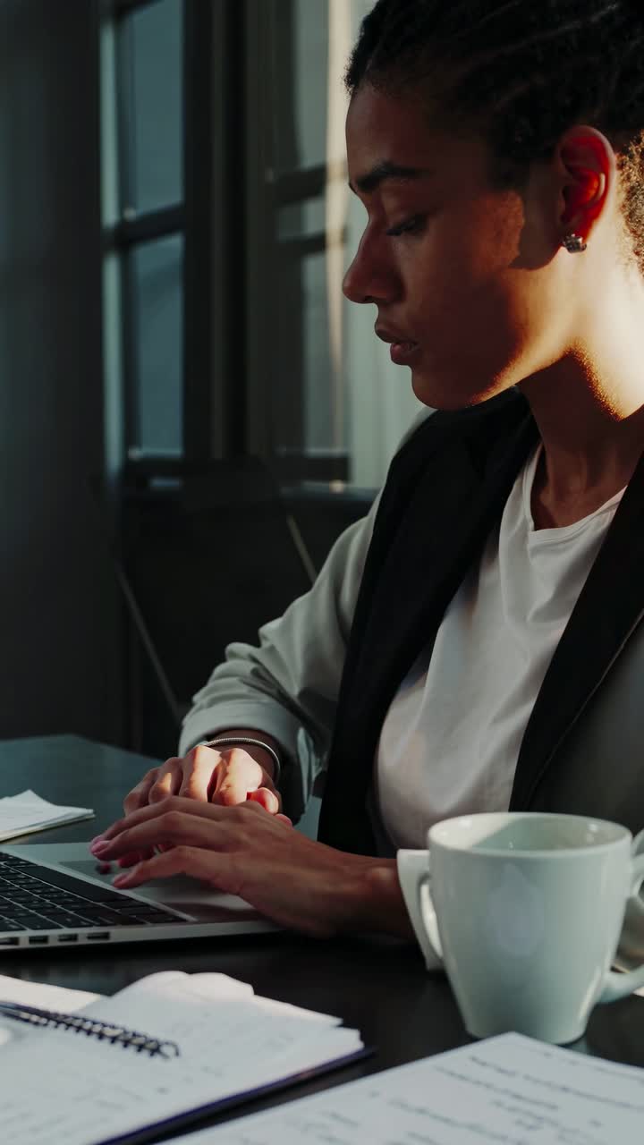 Una foto laterale angolata di una persona concentrata che lavora su un laptop in un ufficio moderno