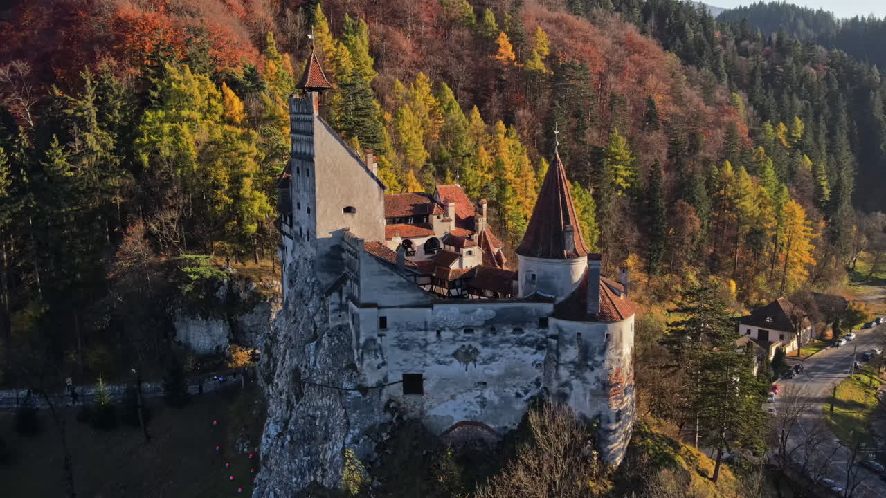 Vista aerea con drone del Castello di Bran in Romania. Castello medievale nei Carpazi, alberi ingialliti, turisti
