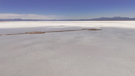 aerial drone descend and tilt up overlooking the route 52 causeway dividing the white salinas grandes of jujuy and salta provinces, argentina