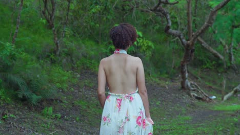 joven latina caminando en un parque en un día soleado con un largo vestido de flores