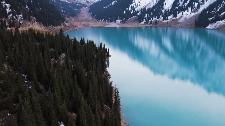 Vista aerea che si inclina sulla foresta presso il Lago Grande di Almaty nel Kazakistan innevato.
