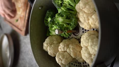 vertical of chopped cauliflower and broccoli placed on steamer pan