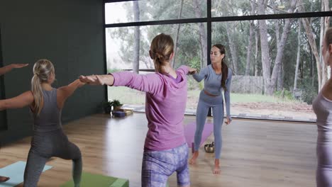 Focused-diverse-women-stretching-together-on-mats-in-yoga-class-with-female-coach,-slow-motion