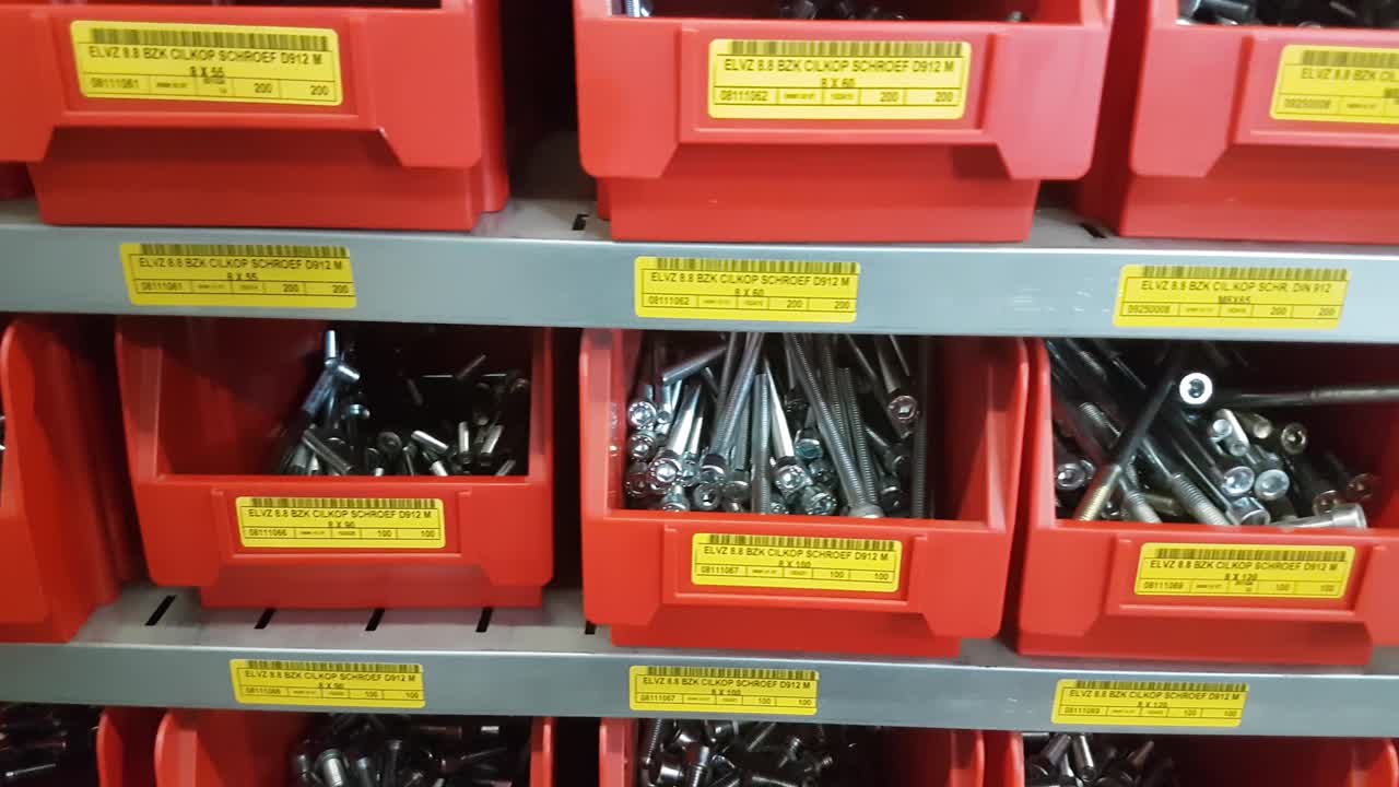 Steel industrial rack with red storage bins with mechanical mounting parts such as nuts, bolts and other parts. CLOSE UP