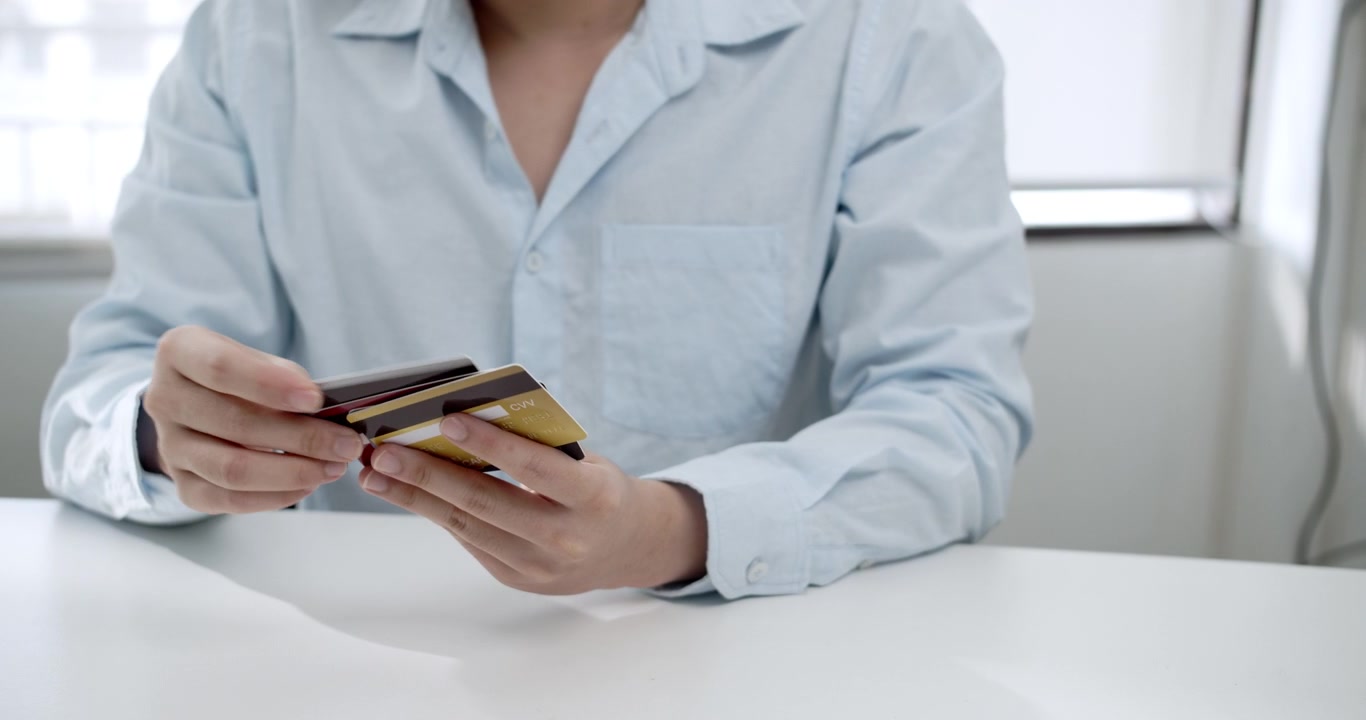 Una persona effettua un pagamento online utilizzando carte di credito, mostrando il passaggio alle transazioni digitali nella finanza moderna.
