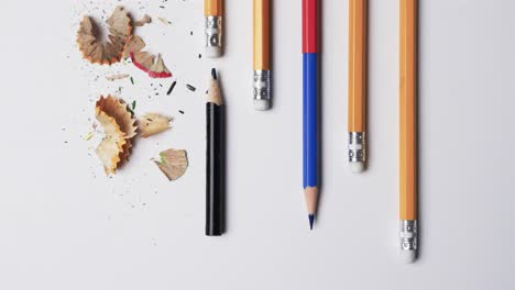 overhead view of pencils and pencil sharpener on white background, in slow motion