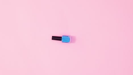 botellas de esmalte de uñas de manicura que giran y cambian de color sobre un fondo rosa pastel. detenga el movimiento