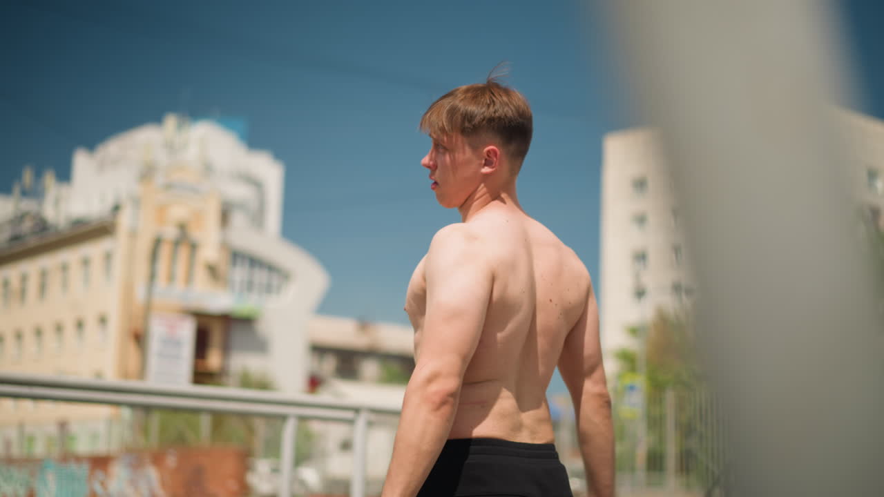 화창한 날씨에 혼자 스트레칭하는 모습, 활동 중에 옷을 편안하게 고쳐 입으며 휴식을 취하는 사람, 따뜻한 날 야외에서 스트레칭 운동을 하는 남성