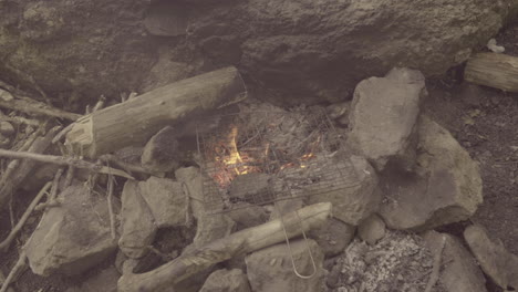 old grill rests on stones around a bonfire in a italian forest, 4k