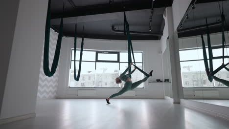 Joven-Hermosa-Mujer-Practica-En-Aero-Estiramiento-Swing.-Una-Mujer-Joven-Gira-Su-Cabeza-Boca-Abajo-En-Una-Hamaca-Para-Practicar-Yoga-Aéreo.-Mujer-Bastante-Madura-Enfocada-Haciendo-Yoga-Aéreo-En-El-Gimnasio