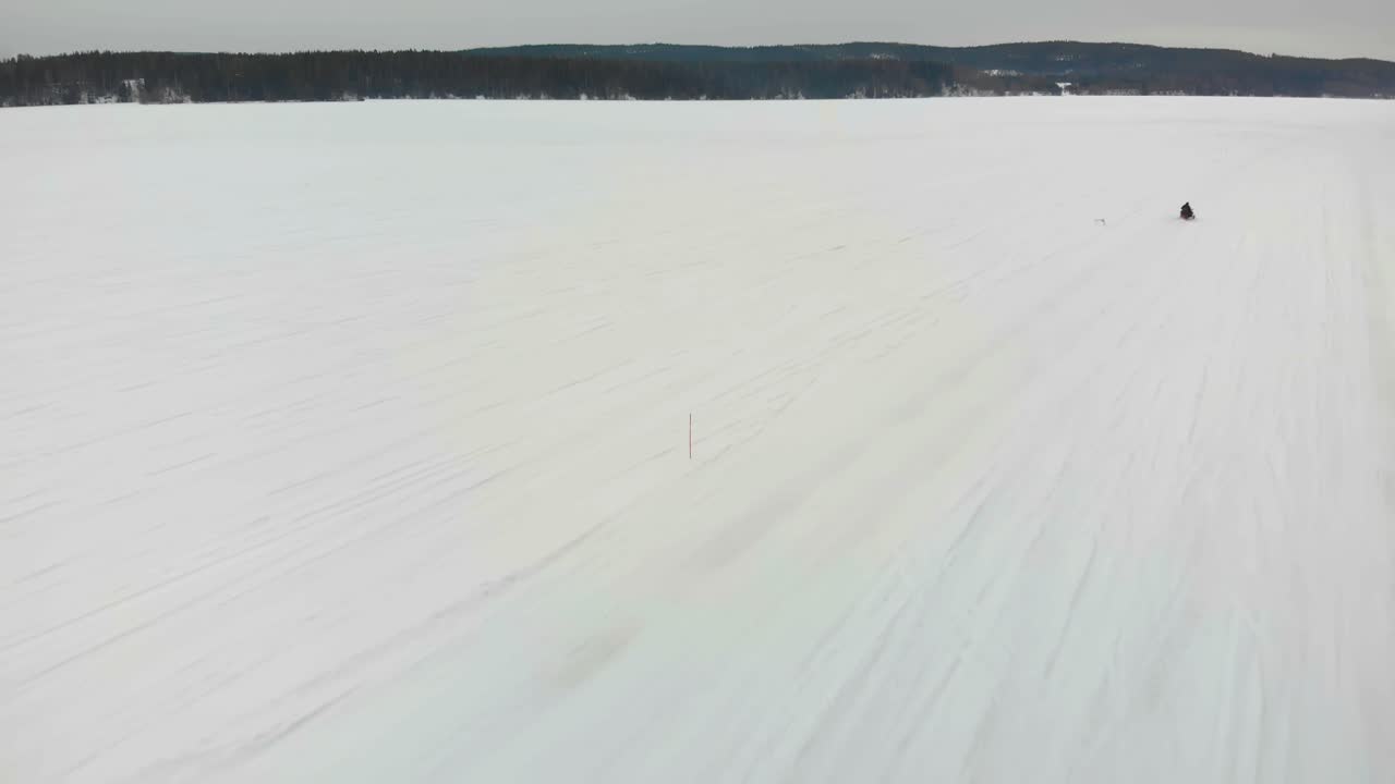 toma aérea de seguimiento de un hombre conduciendo su moto de nieve en indalsalven en timra, sundsvall, suecia
