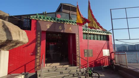 profile view of architecture of tin hau temple with flags waving during a clear sunny day in lei yue mun, hong kong