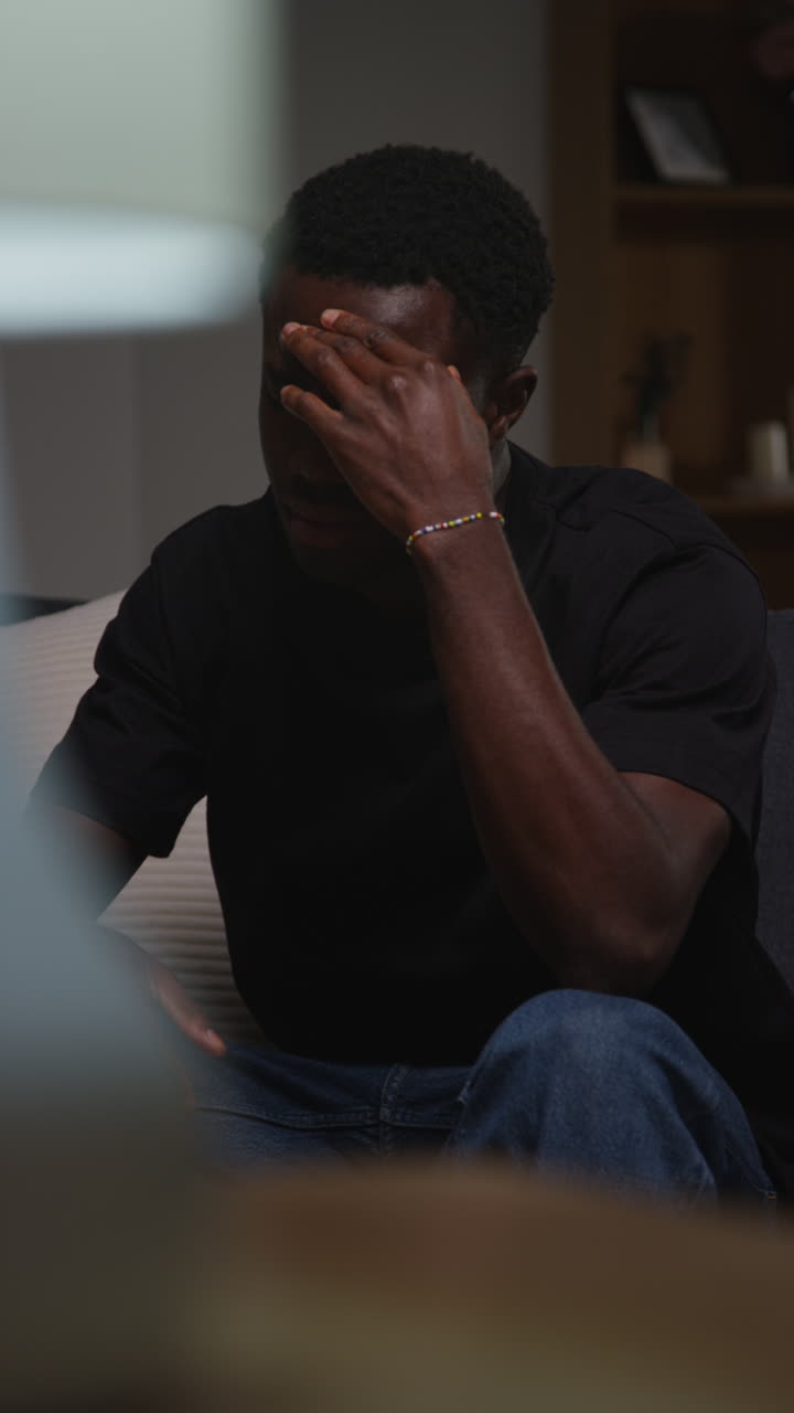 Vertical Video Of Unhappy And Depressed Young Man Sitting On Sofa At Home Looking Anxious And Worried Resting Head On Hand 10