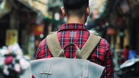 handheld view of tourist with backpack walking in vietnamese street