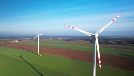 aerial view of pair of wind turbines with spinning propellers in green field