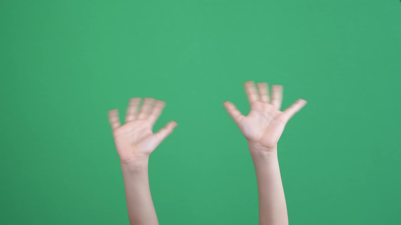 아이의 손을 가까이 들고 인사하고, 작별 인사를 하고, 초록색 배경에 손짓을 합니다.