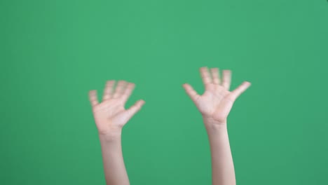 close up of kid hands waving saying greeting, goodbye making hand gestures on green background