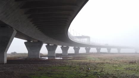 ghostly misty concrete support structure under motorway flyover pan left