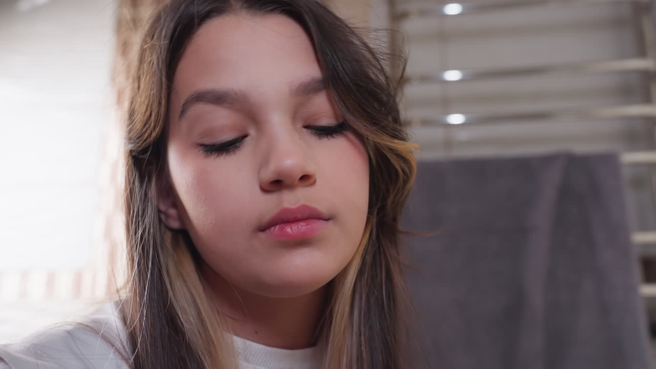 Closeup young daughter focused on task in bathroom, curtain behind, soft light and calm mood, side profile with long hair, natural makeup, intent expression during self care routine