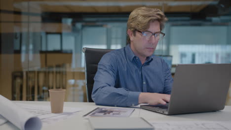 mid-aged architect working on laptop at office desk
