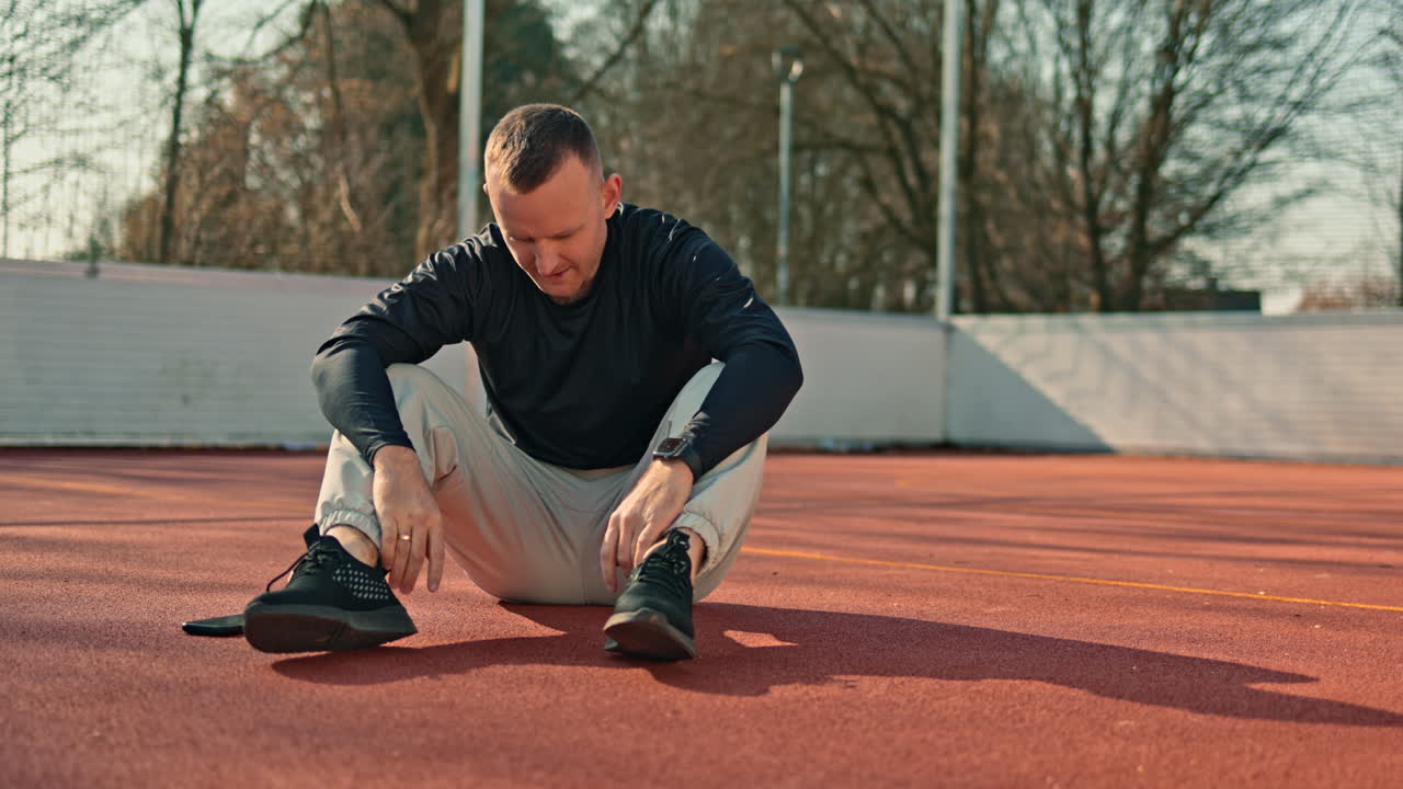 A man is doing sports on a sports ground outdoors. A man is working on his body in the summer doing exercises for body correction