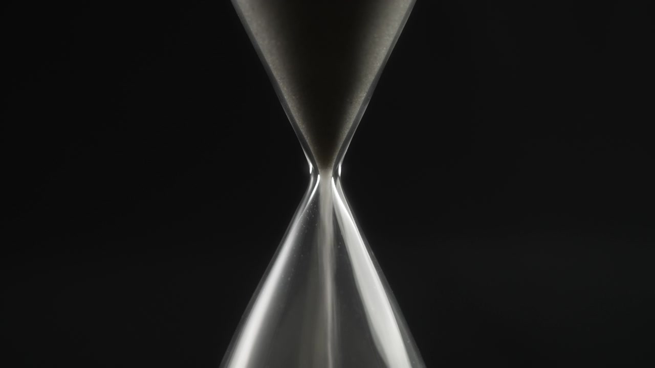 Close-up of Sand Flowing Through a Glass Hourglass