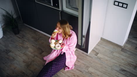 Pretty-woman-sitting-on-floor-in-kitchen-and-eating-sweets.-Satisfied-girl