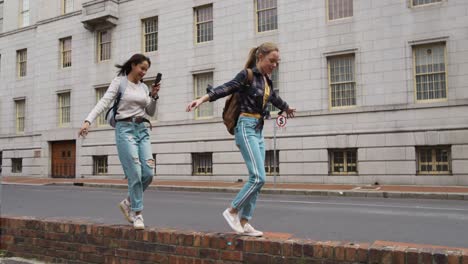 Side-view-of-mixed-race-girl-in-the-street-filming-her-friend