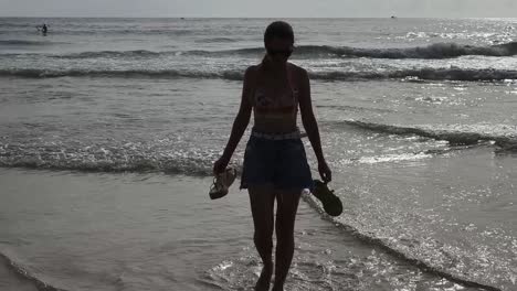 woman walking on the beach with shoes in hand