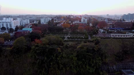 Blick-Auf-Den-Sonnenuntergang-über-Einem-Wohngebiet-Mit-Herbstbäumen,-Luftaufnahme,-Ruhige-Stimmung