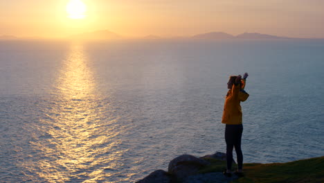 una mujer disfrutando de la puesta de sol sobre el océano.