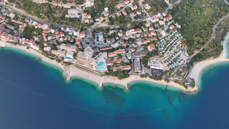 top down view of vibrant beach, hotels, promenade, and turquoise water in podgora, croatia