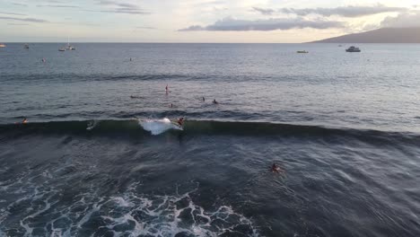 areal shot of surfer catching a wave at sunset in hawaii