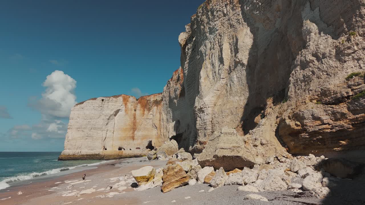 Ground-level view of massive chalk cliffs at Étretat with boulders on the beach, Normandy, France