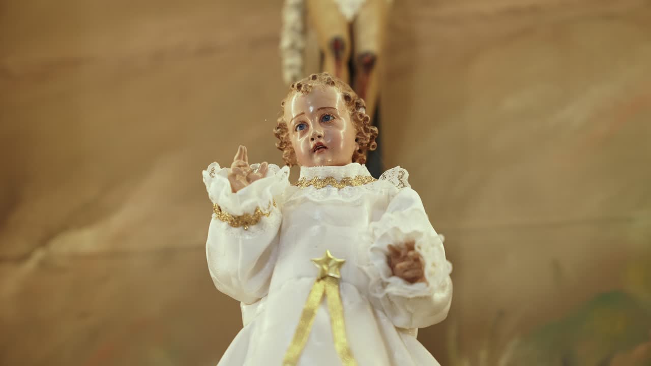 close up of baby jesus statue in white robe with gold accents