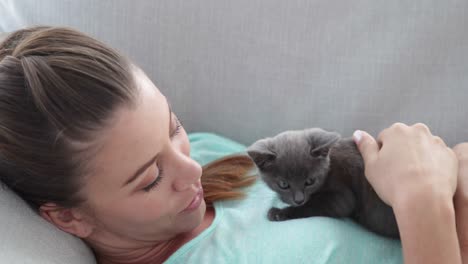 Mujer-Bonita-Tumbada-En-El-Sofá-Jugando-Con-Un-Gatito-Pequeño