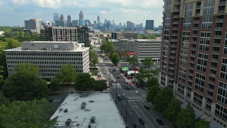 aerial establishing shot of traffic on main street of atlanta city. downtown with skyscraper buildings in background. sunny day in spring season with high-rise apartment blocks. push back flight.