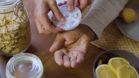 senior black man taking pills from weekly pill organizer.