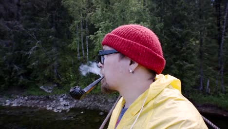 hombre fumando pipa en un puente en un bosque
