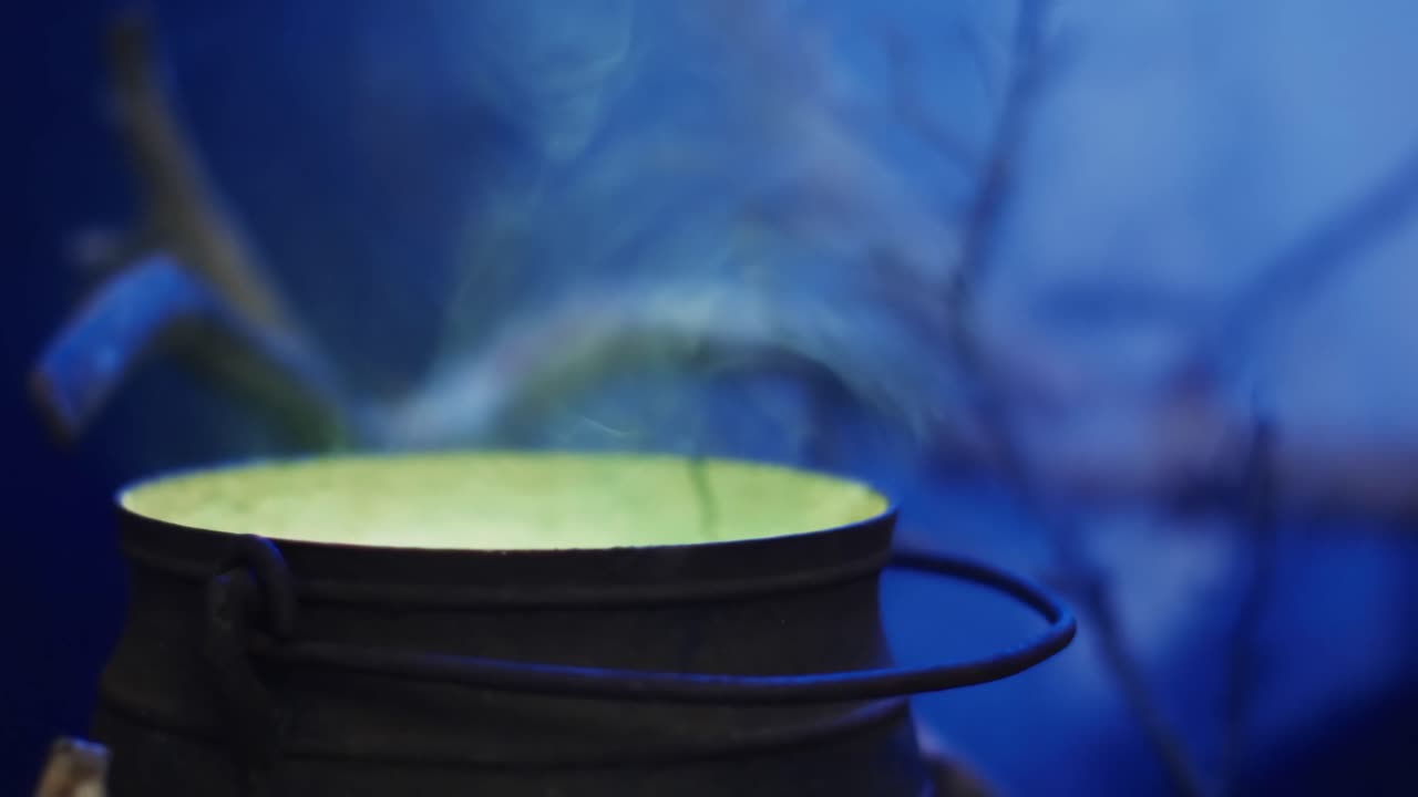 video de una olla con líquido verde y humo sobre un fondo azul