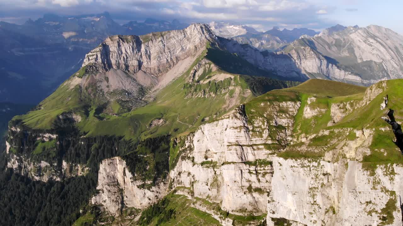 vista aérea de niederbauen chulm en una mañana dorada de verano en los alpes suizos con una vista giratoria de los acantilados del pico, los fiordos del lago lucerna, uri, mitos y el sol naciente
