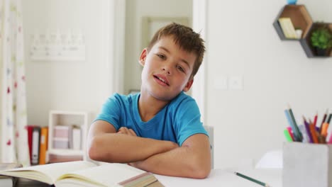 retrato de un niño caucásico con los brazos cruzados sonriendo mirando a la cámara en casa