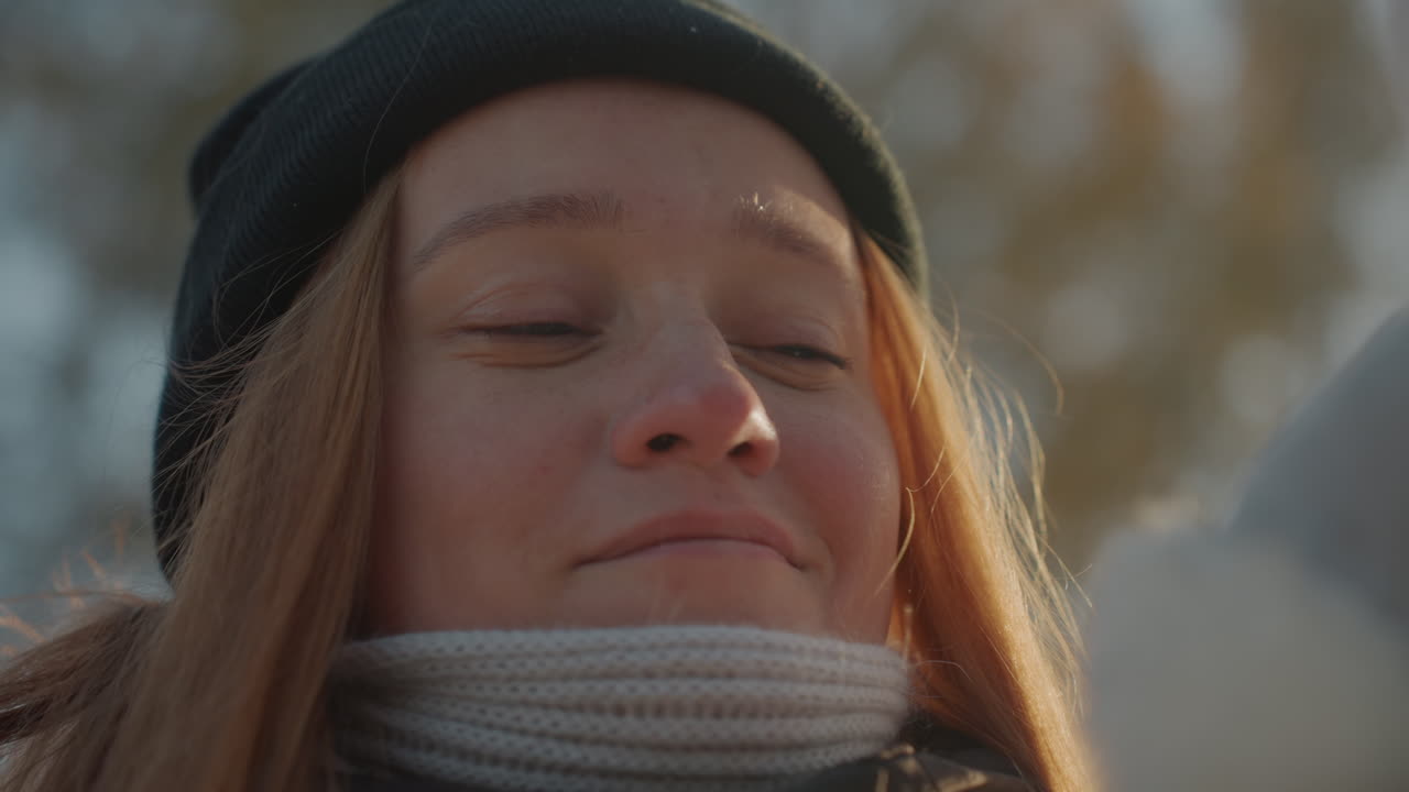 Giovane donna bianca con un coniglio di peluche, berretto e sciarpa. Coccole ravvicinate e un sorriso dolce. Un'escursionista che si ferma nel parco, sogno ad occhi aperti di studentessa, ricordo nostalgico rievocato, coccola giocosa, ritratto intimo.