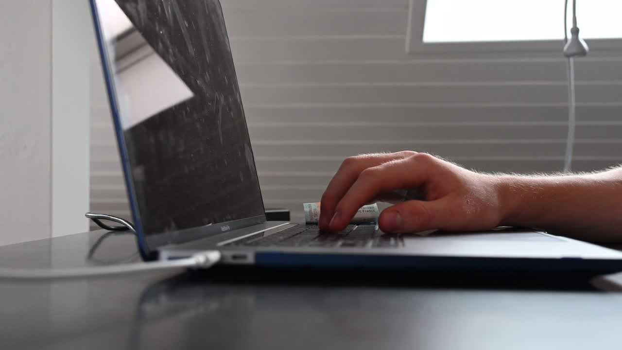 un usuario de una computadora portátil está escribiendo en el teclado, trabajando en su escritorio, los billetes caen en sus manos