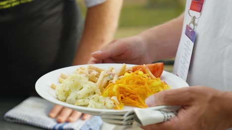 primer plano de un hombre asando salsa y carne, sirviendo comida en un plato