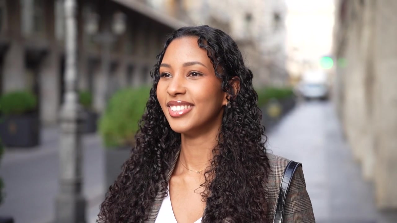 Uma mulher confiante com belos cabelos cacheados caminhando graciosamente em um ambiente urbano vibrante