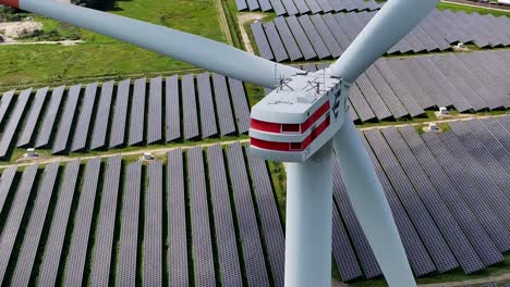 a wind turbine stands tall in the middle of a solar field, surrounded by solar panels