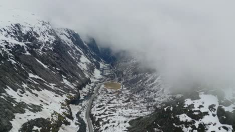 Eerie-drone-shot-of-single-road-in-the-valley-under-the-clouds