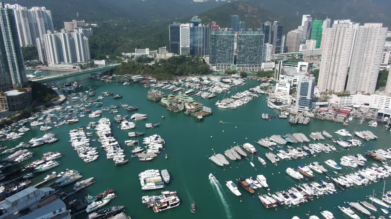 Hong Kong marina and Typhoon shelter with the famous Jumbo floating restaurant, skyscrapers and hundreds of small boats on a clear Summer day, Aerial pull up view.